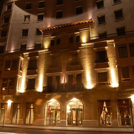 ホテル オテル アラメーダ パラス サラマンカ エクステリア 写真 The photo shows the exterior of a building, likely a hotel, illuminated at night. The facade features a combination of decorative architectural elements, including a prominent entrance framed by large windows. Soft lighting highlights the building's 