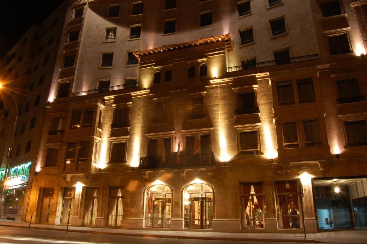 ホテル オテル アラメーダ パラス サラマンカ エクステリア 写真 The photo shows the exterior of a building, likely a hotel, illuminated at night. The facade features a combination of decorative architectural elements, including a prominent entrance framed by large windows. Soft lighting highlights the building's 