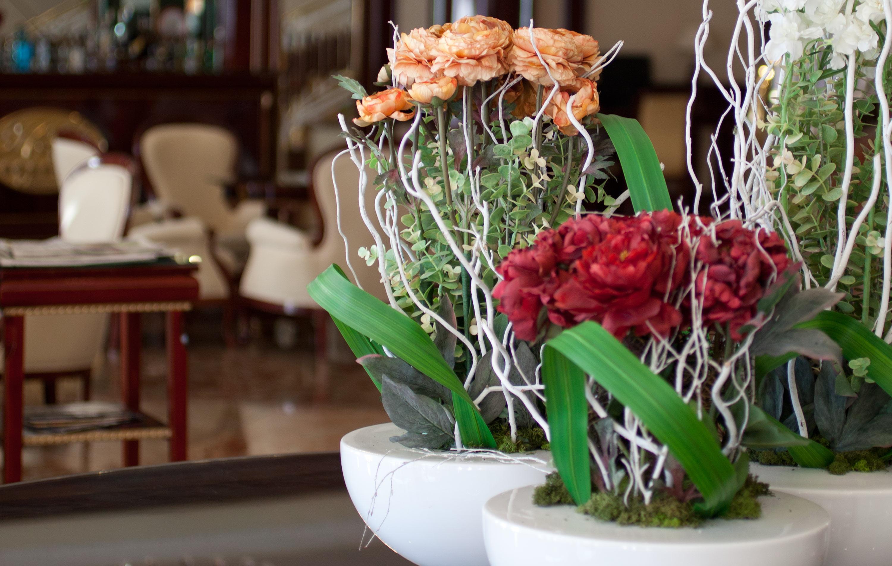 ホテル オテル アラメーダ パラス サラマンカ エクステリア 写真 The photo displays decorative potted plants featuring artificial flowers. There are clusters of blooms in shades of orange and red, complemented by green leaves. The plants are arranged in simple, modern white pots with some decorative branches, prov