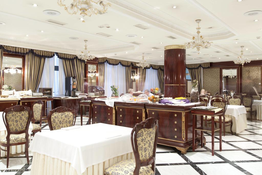ホテル オテル アラメーダ パラス サラマンカ エクステリア 写真 The photo depicts an elegant dining area or restaurant. It features several tables covered with white tablecloths and surrounded by ornate chairs. The room has a classic design with decorative curtains and chandeliers hanging from the ceiling. In the